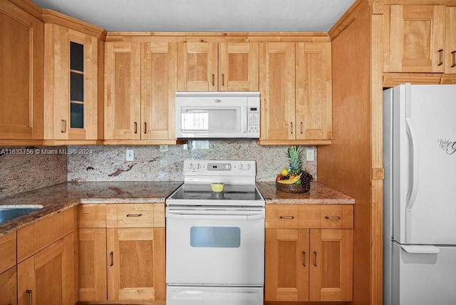 kitchen with white appliances, decorative backsplash, and stone counters