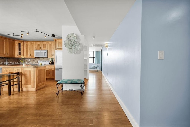 kitchen featuring tasteful backsplash, range, stainless steel refrigerator, a kitchen breakfast bar, and light hardwood / wood-style floors