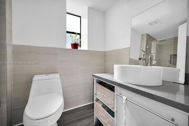 bathroom featuring walk in shower, toilet, tile walls, vanity, and hardwood / wood-style flooring