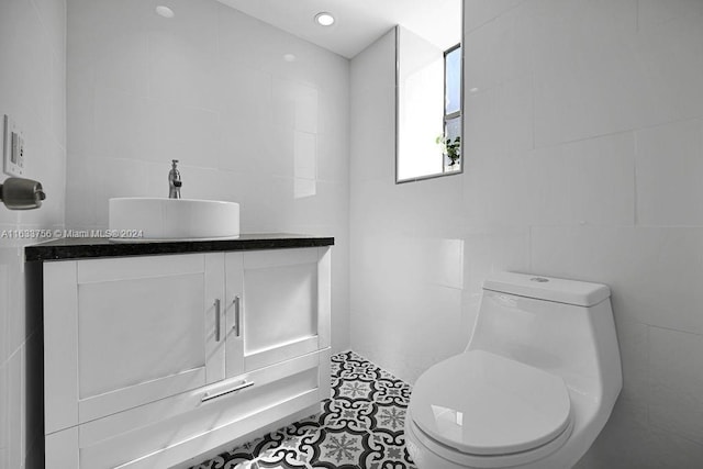 bathroom featuring vanity, tile walls, and toilet