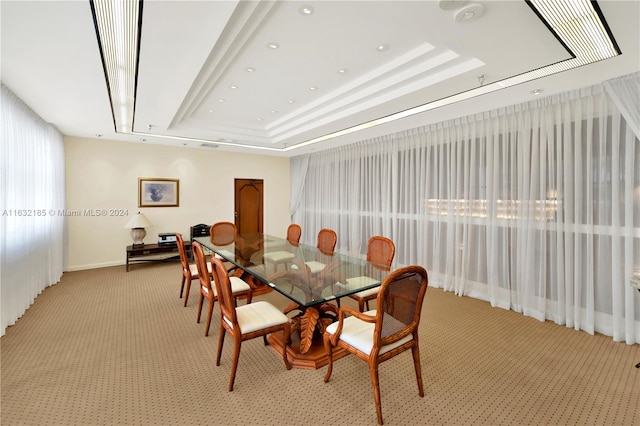 carpeted dining space with a tray ceiling