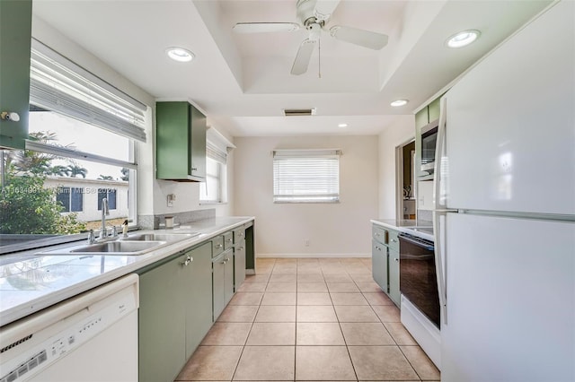 kitchen with white appliances, light tile patterned floors, ceiling fan, green cabinets, and a raised ceiling