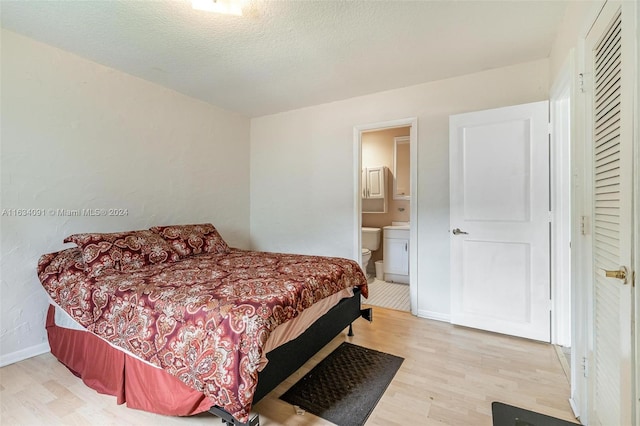 bedroom featuring ensuite bath, a textured ceiling, and light hardwood / wood-style floors