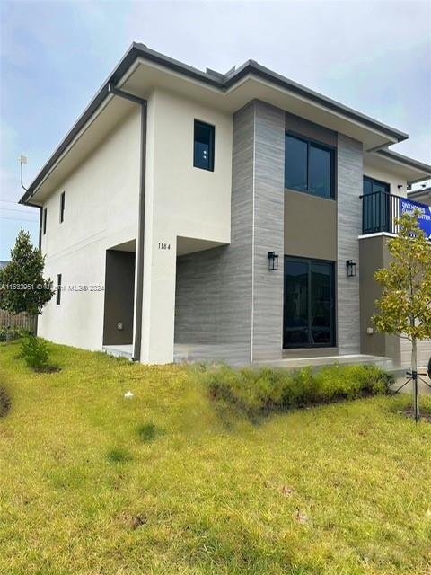 rear view of house with a balcony and a lawn