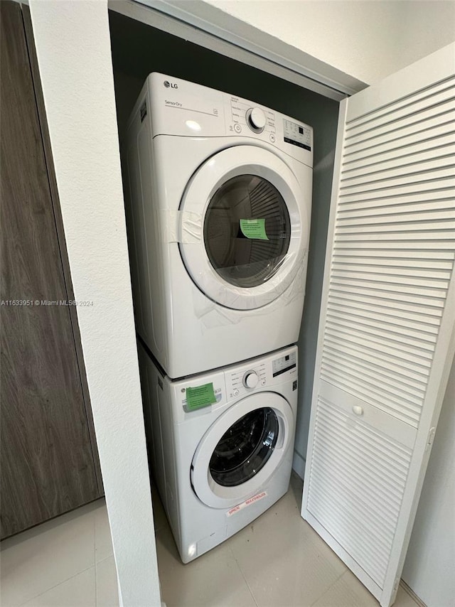 clothes washing area featuring stacked washer / dryer and light tile patterned flooring