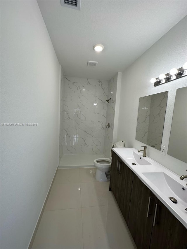 bathroom featuring dual vanity, tiled shower, tile patterned flooring, and toilet