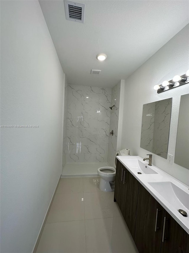 bathroom with dual vanity, toilet, tile patterned floors, and a tile shower