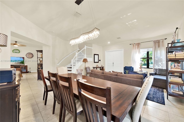 tiled dining room featuring ceiling fan with notable chandelier