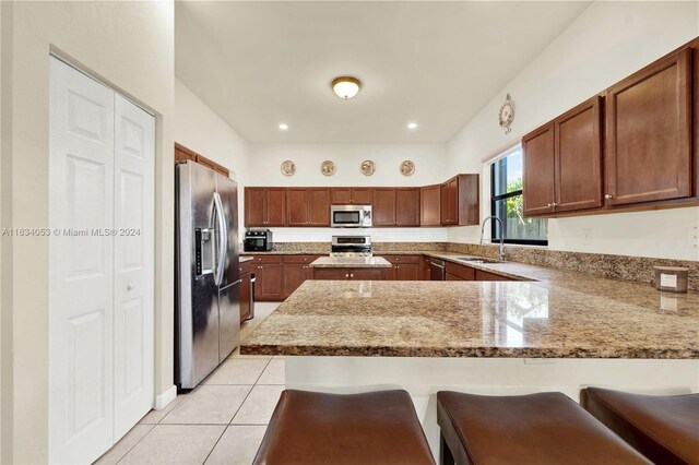 kitchen with appliances with stainless steel finishes, a breakfast bar area, kitchen peninsula, and sink