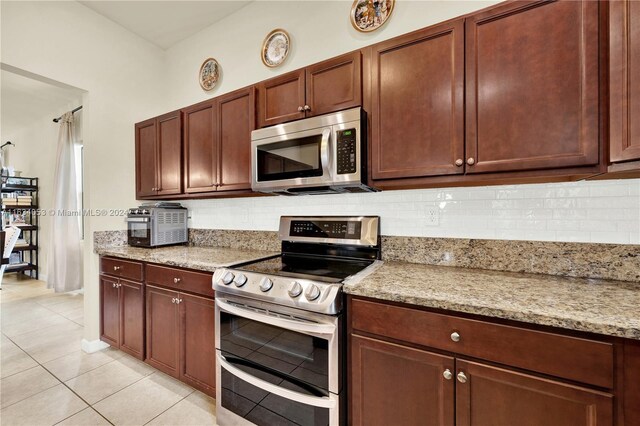 kitchen with backsplash, light tile patterned floors, light stone counters, and stainless steel appliances