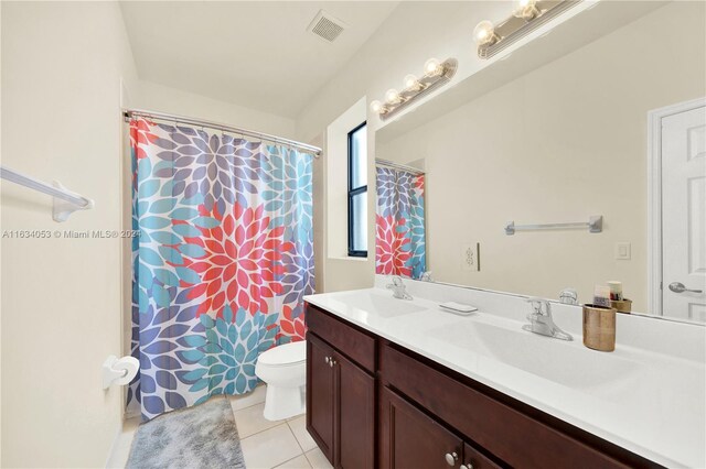 bathroom featuring dual vanity, tile patterned flooring, and toilet