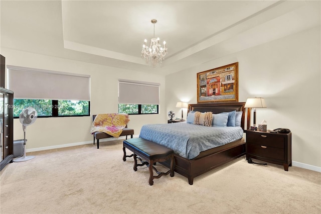 carpeted bedroom featuring a tray ceiling and a notable chandelier