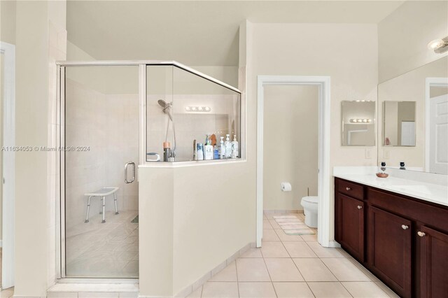 bathroom with tile patterned flooring, a shower with door, toilet, and vanity