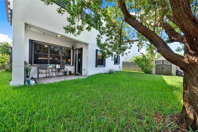 rear view of property with a storage shed, a patio area, and a lawn