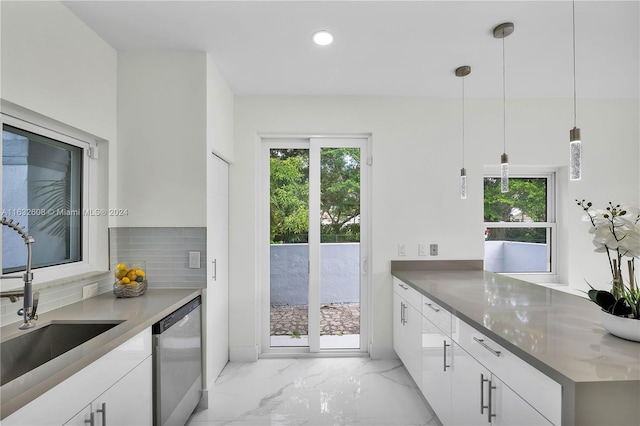 kitchen with pendant lighting, backsplash, sink, stainless steel dishwasher, and white cabinetry