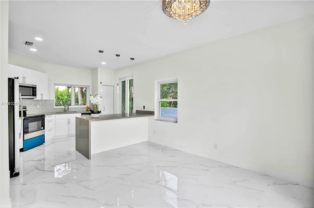 kitchen with electric range, a healthy amount of sunlight, white cabinetry, and hanging light fixtures