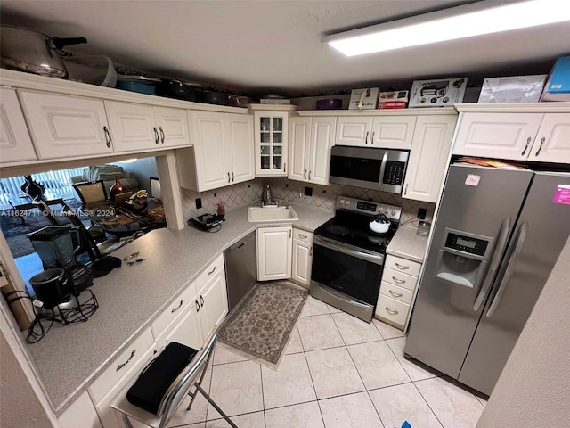 kitchen featuring light tile patterned flooring, stainless steel appliances, white cabinets, sink, and backsplash