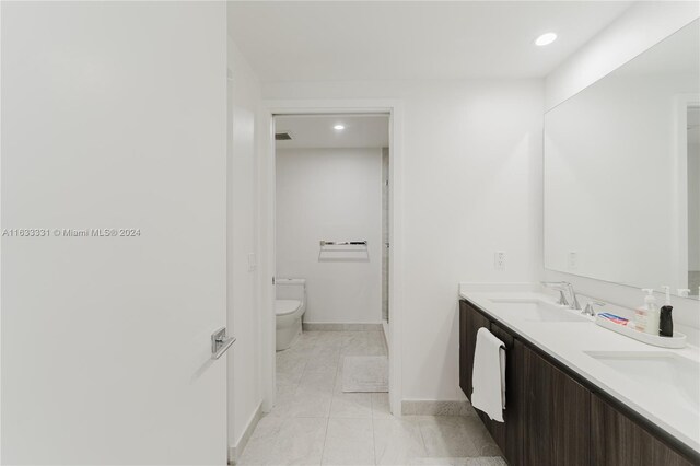 bathroom with tile patterned floors, toilet, and dual bowl vanity