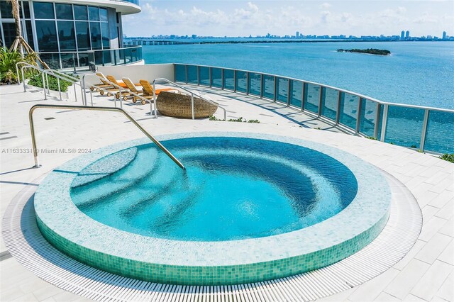 view of swimming pool featuring an in ground hot tub and a water view