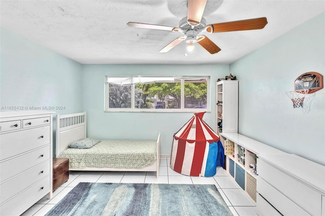 tiled bedroom featuring ceiling fan and a textured ceiling