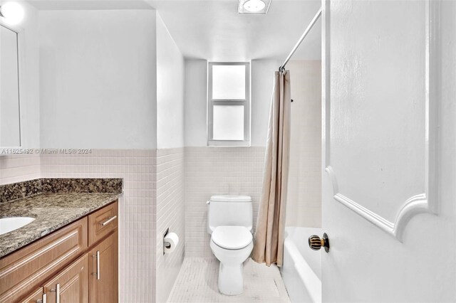 full bathroom with shower / tub combo with curtain, toilet, tile walls, vanity, and tile patterned flooring