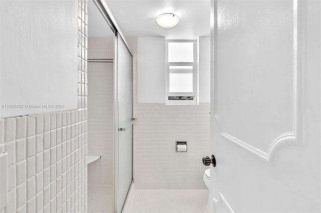 bathroom with walk in shower, toilet, and tile walls