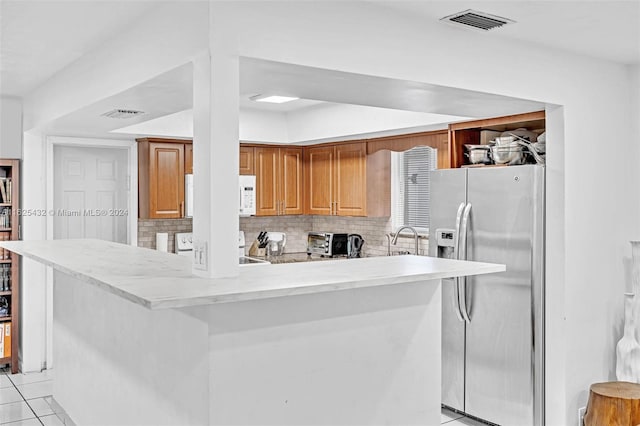 kitchen with sink, range, backsplash, stainless steel refrigerator with ice dispenser, and kitchen peninsula