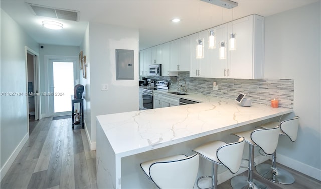 kitchen with white cabinets, light hardwood / wood-style floors, appliances with stainless steel finishes, and kitchen peninsula