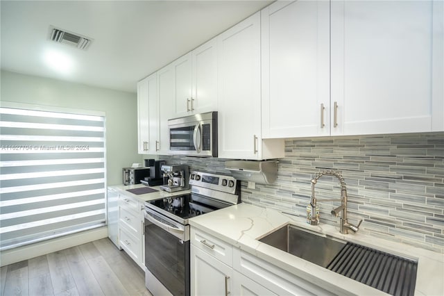 kitchen with white cabinetry, backsplash, appliances with stainless steel finishes, and sink