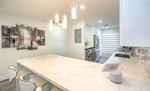 kitchen with white cabinetry, light stone counters, hardwood / wood-style flooring, and decorative light fixtures