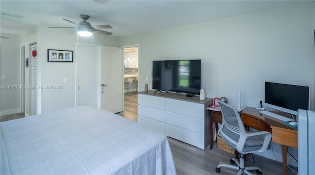 bedroom with ensuite bath, a textured ceiling, ceiling fan, and light hardwood / wood-style floors