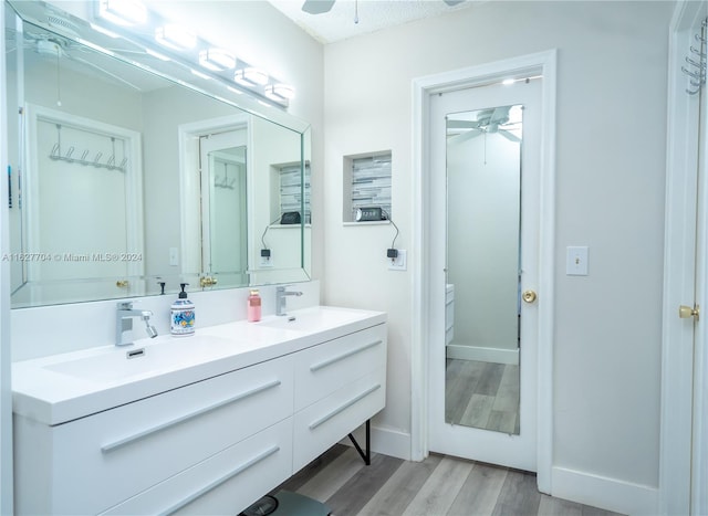 bathroom with wood-type flooring, ceiling fan, and dual bowl vanity