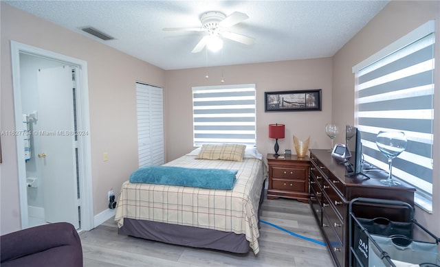 bedroom featuring a closet, a textured ceiling, ceiling fan, and light wood-type flooring