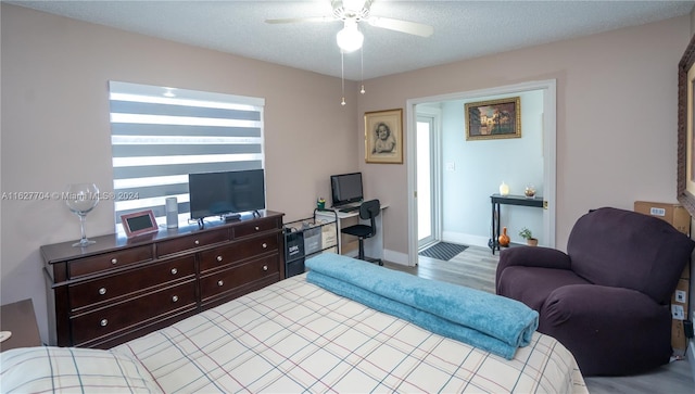 bedroom with hardwood / wood-style flooring, a textured ceiling, and ceiling fan