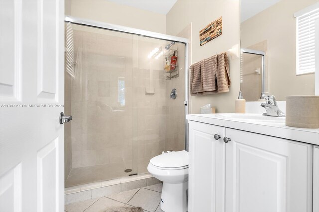 bathroom with tile patterned flooring, vanity, toilet, and a shower with door