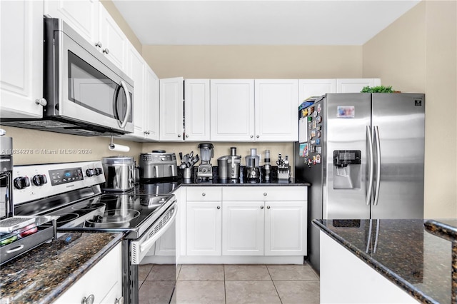 kitchen featuring white cabinets, dark stone counters, light tile patterned floors, and appliances with stainless steel finishes