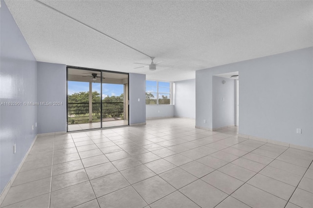 tiled empty room with ceiling fan and a textured ceiling