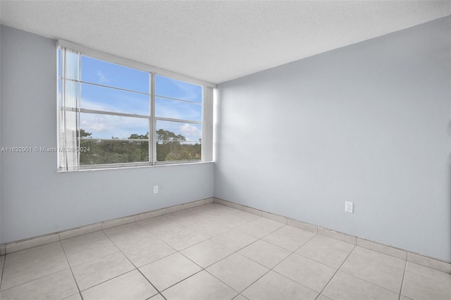 tiled spare room featuring a textured ceiling