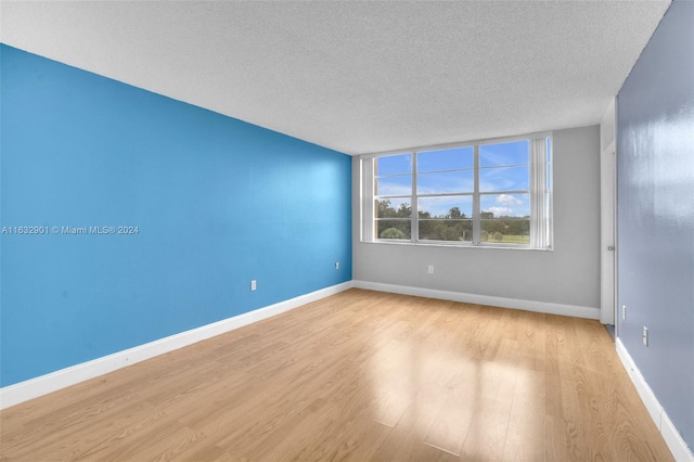 empty room with light hardwood / wood-style floors and a textured ceiling