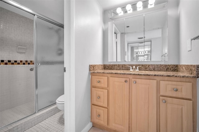 bathroom featuring tile patterned flooring, vanity, an enclosed shower, and toilet