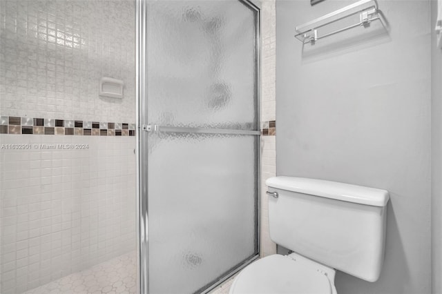 bathroom featuring toilet and a shower with shower door