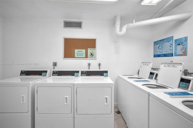 clothes washing area with washer and clothes dryer and light tile patterned floors