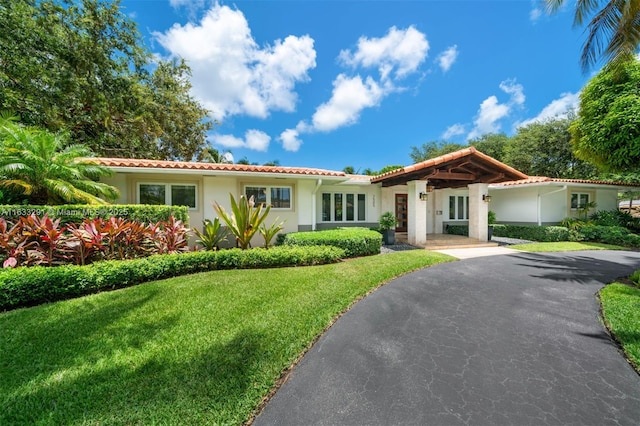 view of front of house with a tiled roof, a front yard, and stucco siding