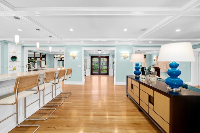 kitchen featuring coffered ceiling, decorative light fixtures, a chandelier, light hardwood / wood-style floors, and plenty of natural light