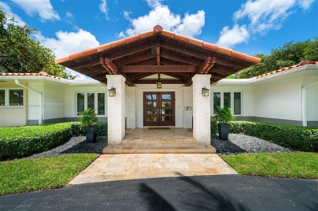 doorway to property with a tiled roof, french doors, and stucco siding