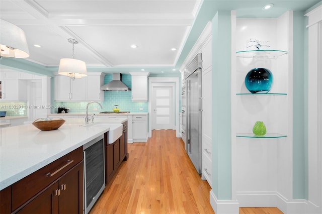 kitchen with decorative light fixtures, white cabinetry, wine cooler, and wall chimney exhaust hood