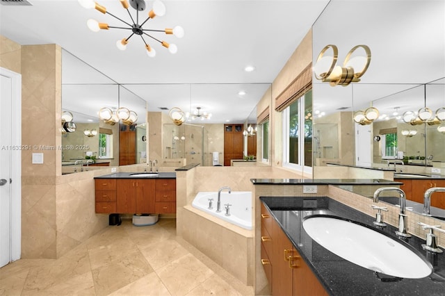 bathroom featuring plus walk in shower, vanity, an inviting chandelier, and tile patterned flooring