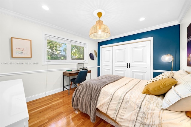 bedroom with light wood-style flooring, a closet, crown molding, and baseboards