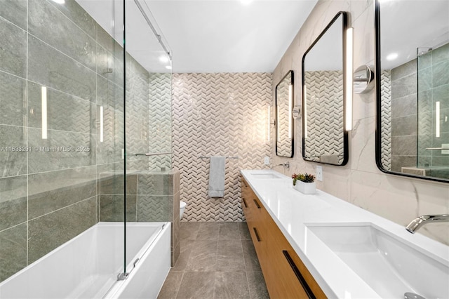 bathroom with tile patterned flooring, vanity, tile walls, and combined bath / shower with glass door