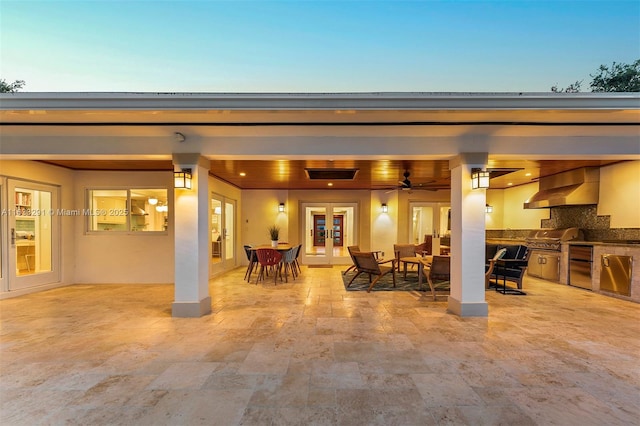 patio terrace at dusk with area for grilling, ceiling fan, and french doors